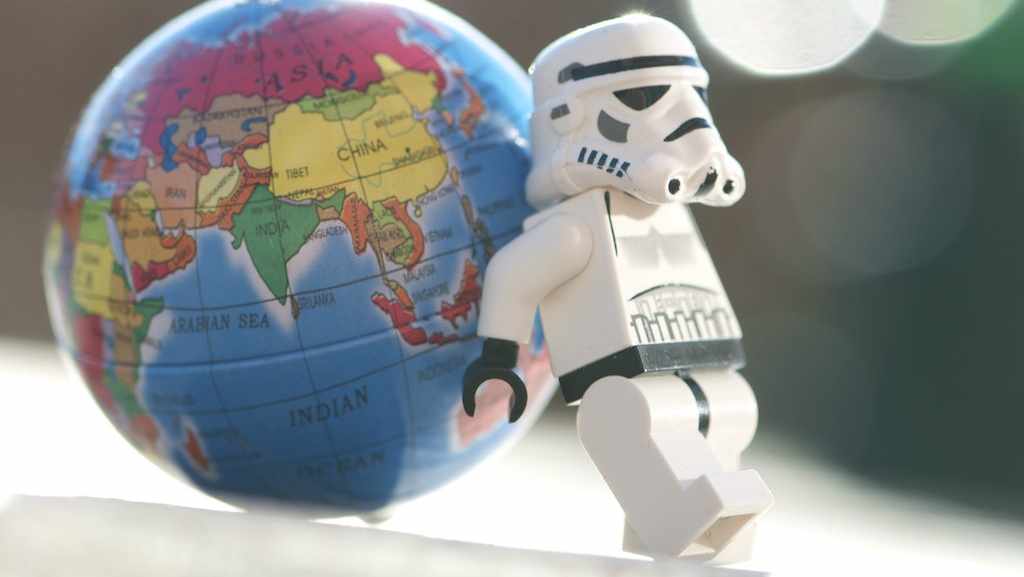 Star Wars lego minifigure leaning on small globe of earth